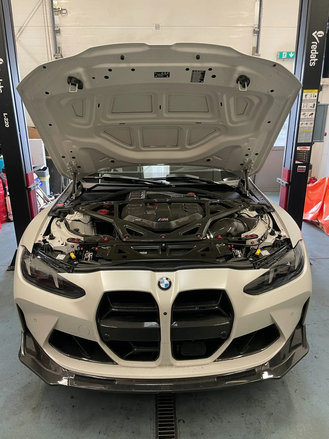 Białe BMW z otwartą maską podczas diagnostyki